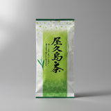 A packaged bag of #0133.K2 Yamane-en: First Flush Saemidori Fukamushicha from Yakushima Island, displayed on a wooden surface.