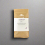 Kurihara coffee package on a wooden surface with a gray background