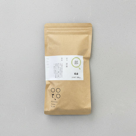 A packaged bag of Tomizawa Tea Garden's Kumamoto Shira-ore Leaf Stem Tea with a label indicating it's a naturally grown green tea product.